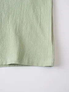 Close-up detail of breathable sage green linen fabric and double-stitched hem finish