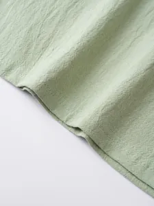 Detailed macro shot showing professional double-needle stitching on light green linen top