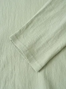 Close-up detail of a men's light green linen long sleeve shirt cuff with fine stitching.