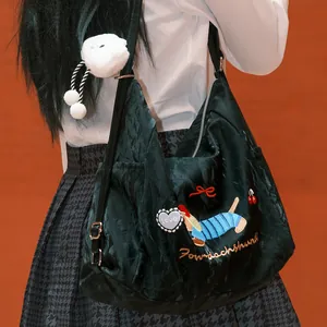 Detalle de bolso bandolera verde oscuro con bordado de perro salchicha y peluche