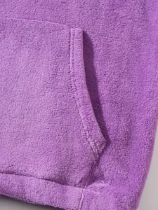 Close-up of plush purple fleece fabric detail showing hooded sweatshirt kangaroo pocket seam.