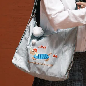 Detalle de primer plano de un bolso bandolera ligero con bordado de un lindo perro salchicha