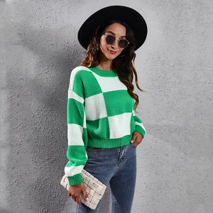 Green and white checkerboard cropped knitted sweater on model against grey wall.