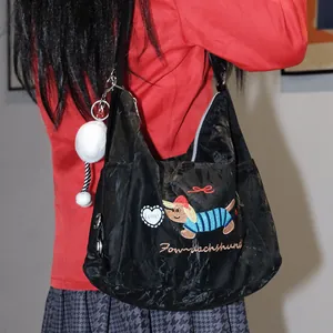 Vista detallada del bolso hobo negro con bordado de perro salchicha y textura rugosa.