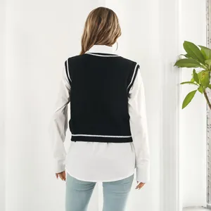 Back view of a knit black vest with white trim layered over a white shirt.