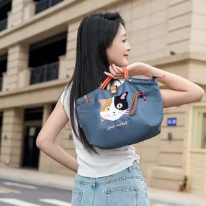 Asiatisches Model mit süßer blauer Tragetasche mit Cartoon-Katzenstickerei-Detail