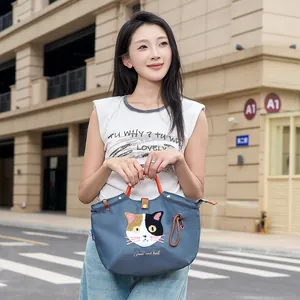 Niedliche blaue Handtasche im japanischen Stil mit Katzenstickerei, von Model getragen.