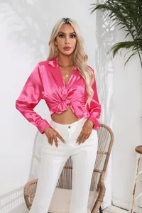 Detail der leuchtend rosa Satinbluse mit Reverskragen und Taillenknoten vorne