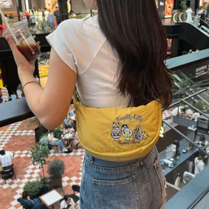 Yellow embroidered crescent bag worn as a stylish underarm shoulder bag in a mall.