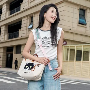 Detailansicht einer süßen Canvas-Tasche mit Katzenstickerei, getragen von einem Model.