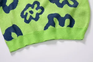 Close-up detail of green floral jacquard knit sweater showing texture and rib hem