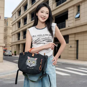 Detailansicht einer süßen schwarzen Tasche mit Katzenstickerei, getragen von einem Model