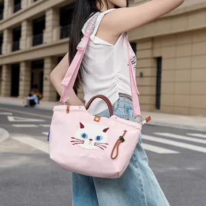 Süße rosa Canvas-Tragetasche mit Katzenstickerei, getragen von einem Model auf der Straße.