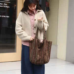 Brown textured wool tote bag with stripes held by model in casual lifestyle setting