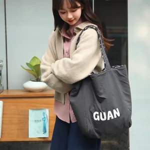 Lifestyle detail of a grey reversible fleece tote bag with white GUAN lettering