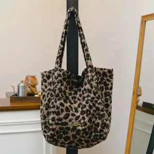 Close-up view of a leopard print wool tote bag with a 'handmade' metal tag detail.
