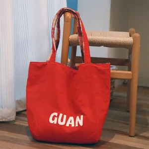 Detailed view of the red wool tote bag featuring white GUAN lettering on a chair