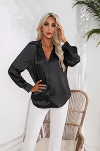Nahaufnahme einer schwarzen Satin-Bluse mit Reverskragen in stilvoller Außenumgebung