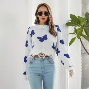 Detail of white Y2K cropped knit sweater with blue butterfly patterns and distressed hem