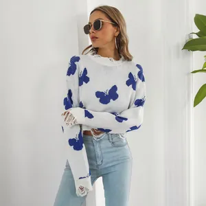 Detailed view of white distressed knit sweater with blue butterfly patterns on a model