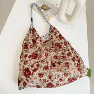 Detailed view of a large capacity floral canvas beach bag on a minimalist white table.