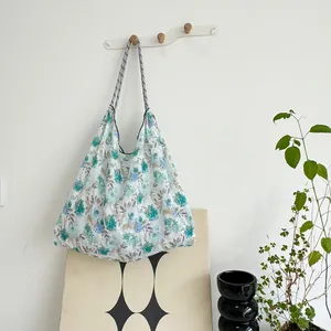 Detailed view of a large floral canvas beach bag hanging on a white wall