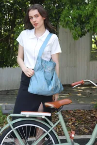 Donna con una borsa tote testurizzata azzurra accanto a una bicicletta d'epoca verde