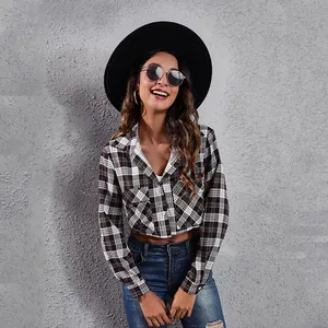 Detailweergave van een stijlvol zwart-wit geruit cropped shirt met lange mouwen op een model.