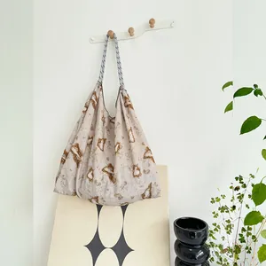 Detailed view of large floral print canvas tote bag hanging on a minimalist white wall hook