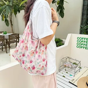 Large capacity floral print canvas tote bag worn by a model in a sunny outdoor cafe.