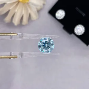 Macro close-up of a round brilliant cut lab-grown blue diamond held with clear tweezers