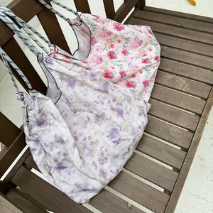 Detailed view of floral and purple tie-dye canvas tote bags on a wooden bench
