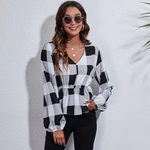 Detailed view of women's black and white buffalo plaid V-neck blouse with lantern sleeves