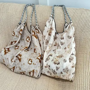 Detailed view of two printed drawstring canvas tote bags on a knitted surface