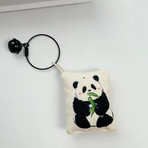 Primer plano de un colgante de panda de lona con un cascabel negro y un aro metálico negro
