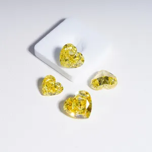 Loose fancy vivid yellow heart-shaped lab-grown diamonds on white display base