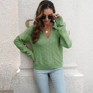 Donna che indossa un maglione lavorato a maglia a scacchi verde con maniche lunghe.