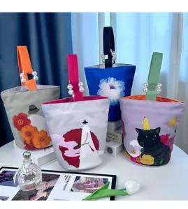 Artistieke canvas emmertassen met luxe parelhandvatten en creatieve illustraties.