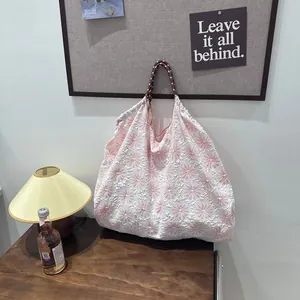 Détail du motif floral rose et blanc texturé sur un sac à bandoulière souple et élégant.