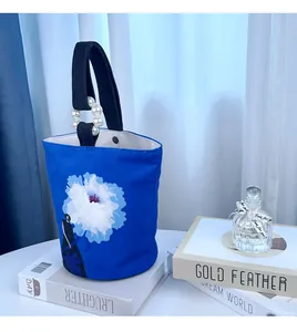 Artistieke blauwe canvas bucket bag met bloemenprint en elegant parelhandvat.