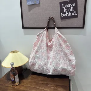 Grand sac à main blanc avec broderie florale rose suspendu dans un décor chaleureux