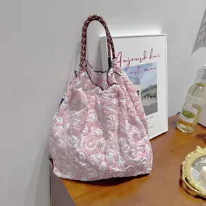 Vue détaillée d'un sac cabas floral rose et blanc avec un motif en relief texturé.