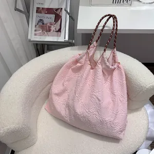 Vue détaillée d'un sac cabas rose à fleurs texturées avec des poignées en corde stylées