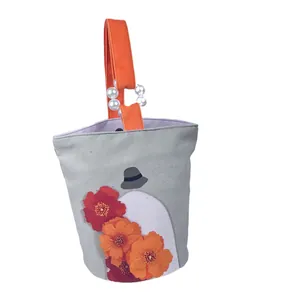 Artistieke canvas emmertas met bloemenprint en een chic detail van parelhandvaten