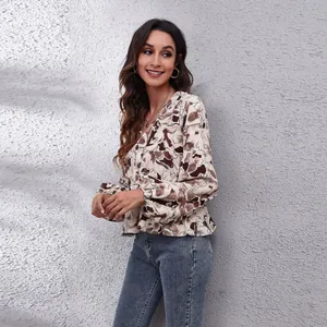 Detailed view of women's V-neck lantern sleeve blouse with abstract brown floral print
