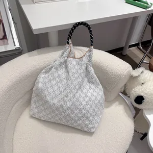 Gros plan du sac cabas blanc à fleurs avec poignée en corde tressée noire et blanche
