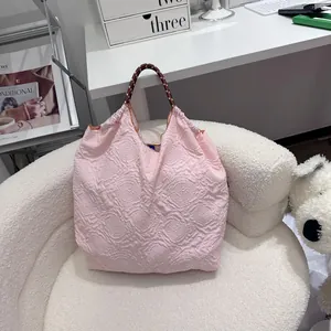 Sac fourre-tout rose à relief floral avec poignée tressée sur un fauteuil