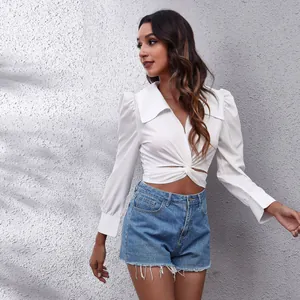 Close-up of white cropped blouse with twist-front detail and elegant puff sleeves.