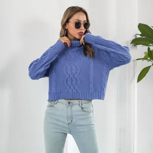Close-up of a blue cable-knit turtleneck cropped sweater worn by a model in a studio.