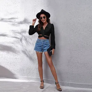 Full body view of a stylish woman in a black cross-tie front puff sleeve cropped shirt.